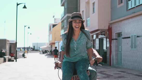 Interracial couple have fun together riding a bike in outdoor in the city - happiness and joy young alt