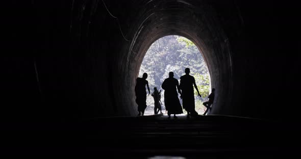 Silhouette of Buddhist Monks Walking Through the Tunnel Into the Light