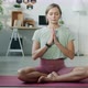 Relaxed Girl in Sportswear Meditating in Lotus Position Sitting on Yoga Mat with Closed Eyes Namaste - VideoHive Item for Sale