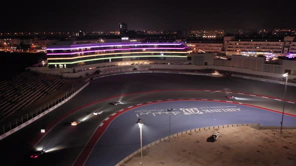 Aerial view of car racing in corner, Dubai Autodrome race track during night endurance competition