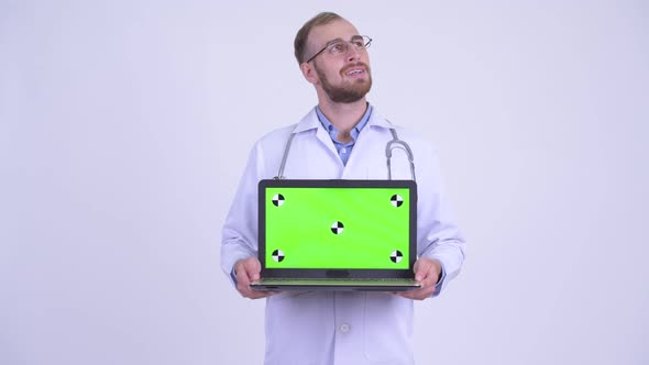 Happy Bearded Man Doctor Thinking While Showing Laptop
