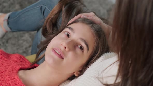 Girl Lies with Her Head on Her Mother's Feet While They Have a Friendly Conversation alt