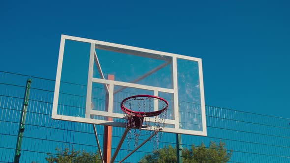 Basketball Rim with Glass Backboard Against Blue Sky alt