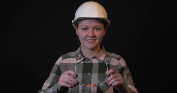 Young Female Engineer Puts on Protective Glasses.