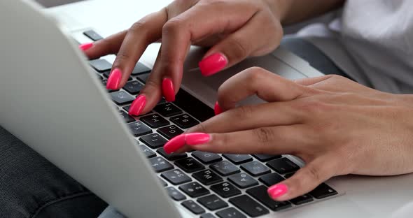 Black woman hands typing on laptop keyboard .