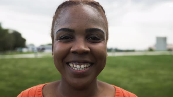 Happy African woman smiling in front of a camera in park alt