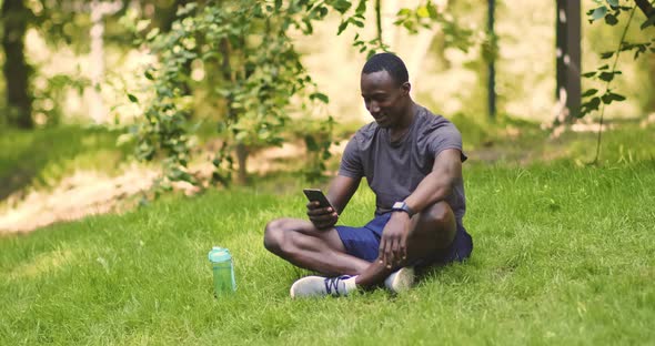 Millennial African American Man Browsing on Smartphone in Park alt