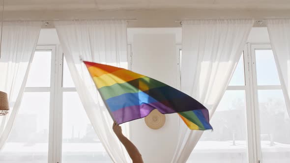 Rainbow LGBT Flag in Hand and Waving on Sunset in Sunny Rays alt