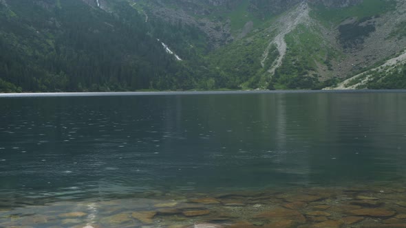 Slow motion footage of raindrops falling into a mountain lake. Hiking in the mountains