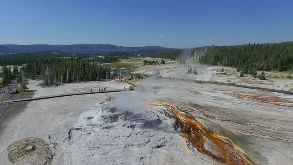 Camera circles a geyser as steam billows out and orange liquid streaming out alt