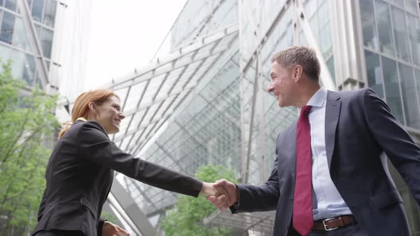 Businesswoman shaking hands with Businessman outdoors in the city