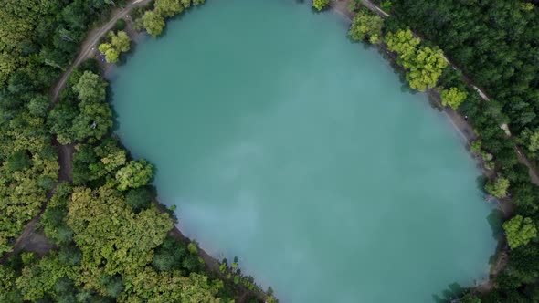Aerial view over a turquoise lake, with a reflection of the passing clouds