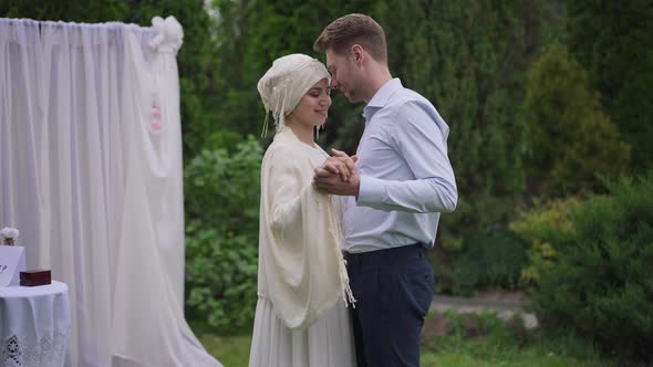 Loving Interracial Young Couple Dancing at Wedding Altar in Summer Garden Outdoors alt