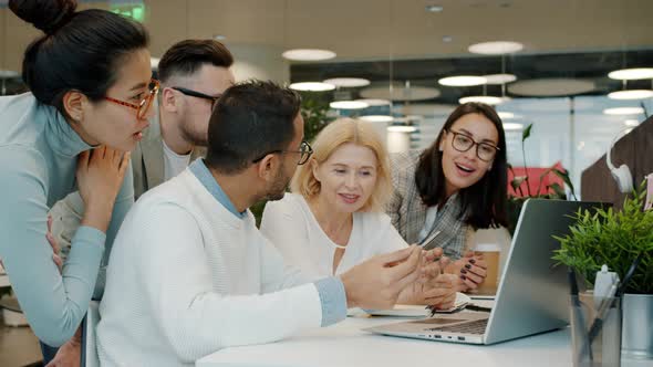 Multiracial Group of People Talking Discussing Work Looking at Laptop Screen in Shared Office alt