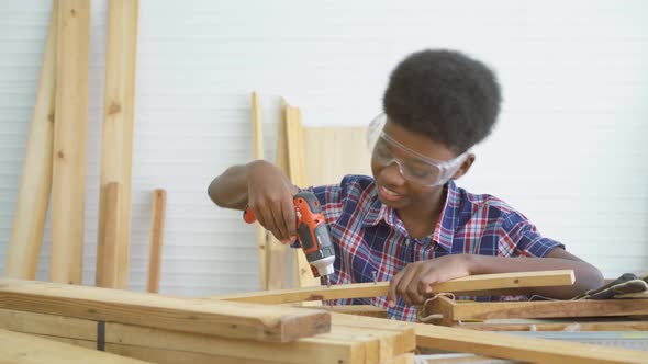 Little child with a drill in hands and help dad assembling furniture shelf with power screwdriver  alt