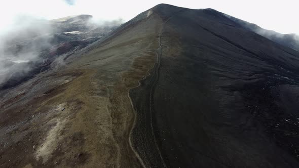 climbing a black snow-covered volcano in the clouds