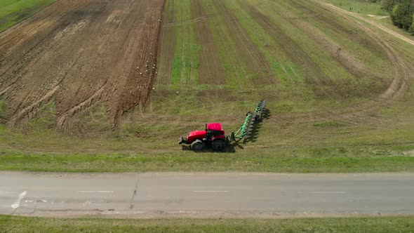 Farmer on a Tractor Turns Around Near the Road and Begins Plowing Farmland in Spring in Sunny alt