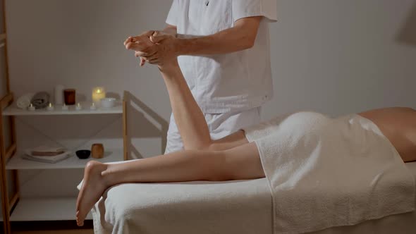 Professional Legs Massage in SPA Salon on the Background of Candles