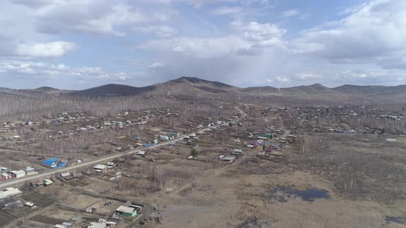 Aerial view of city with private houses. At the background the mountains alt