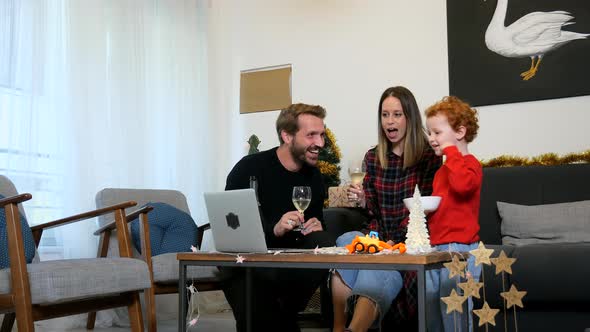 Family using laptop for video call in living room alt