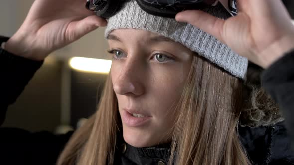 Cute young girl putting on snowboard goggles