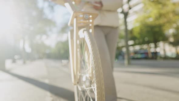 Female Cyclist Walking on Sidewalk alt