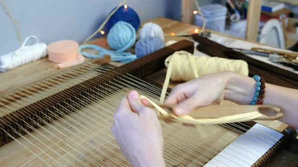 Weaving on a Loom Frame.  Woman's Hands Spool of Yellow Thread on the Shuttle.