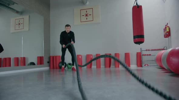 Young man is engaged in crossfit, doing leg exercises, warming up, in the gym. alt