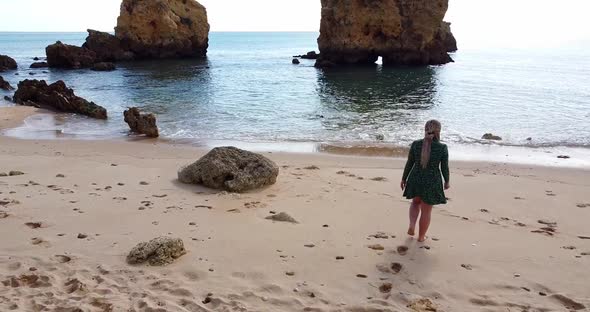 Camera Slowly Tilting Up While a Beautiful Woman is Walking to the Beach alt