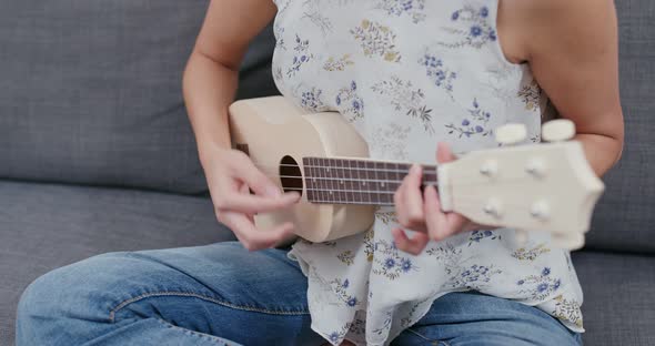 Woman play ukulele at home alt