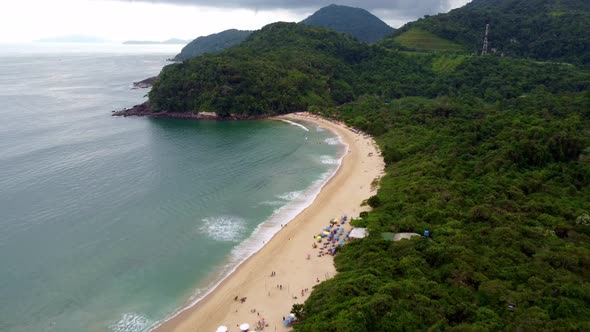 Aerial flying over forest and beach at district of Ubatuba on sunny day, Brazil alt