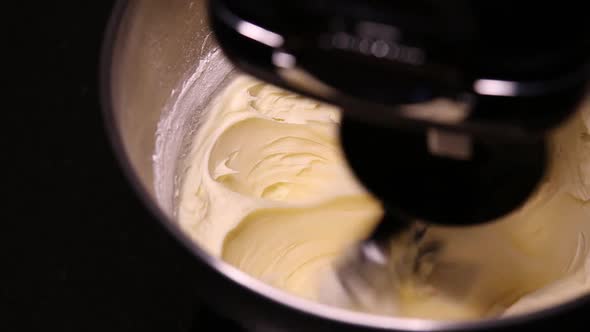 Close up shot of buttercream icing being whipped in a stand mixer. alt