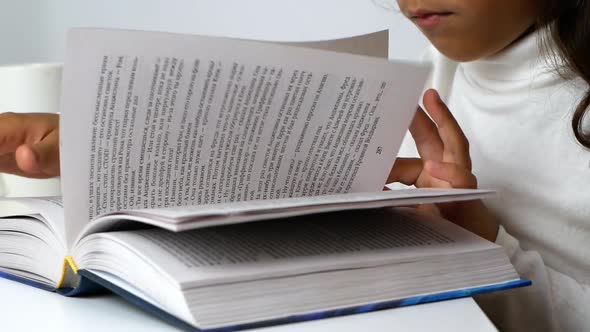 A little girl studies at home during the quarantine period. The child reads a book