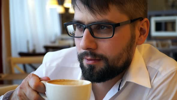 Man Sits in Cafe and Drinks Coffee