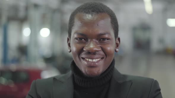 Close-up Face of Young African American Car Dealership Manager Looking at Camera and Smiling alt