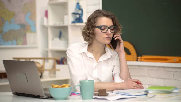 Female Student Studying in University. Young Teacher in Glasses Over Green Chalkboard alt