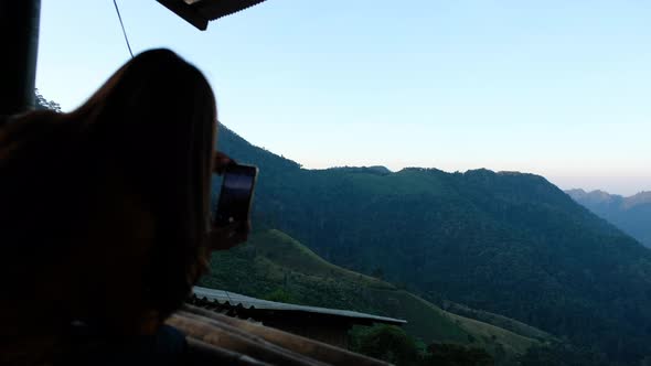 Blurred of a woman using mobile phone to take photo of a beautiful mountain view