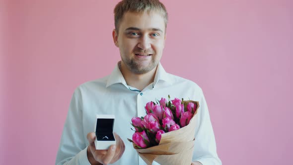 Portrait of Handsome Bearded Guy with Bunch of Flowers and Engagement Ring alt