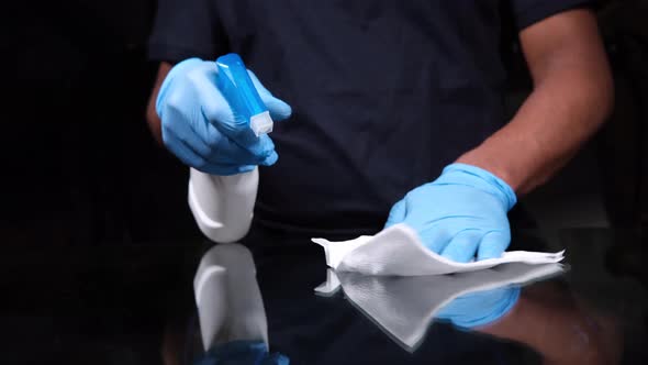 Hand in Blue Rubber Gloves Holding Spray Bottle Cleaning Table alt