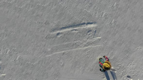 Happy Girl Falls Down at Snow To Create a Snow Angel. Aerial View. alt