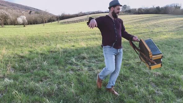 Musician holding his accordion and twisting on a meadow alt