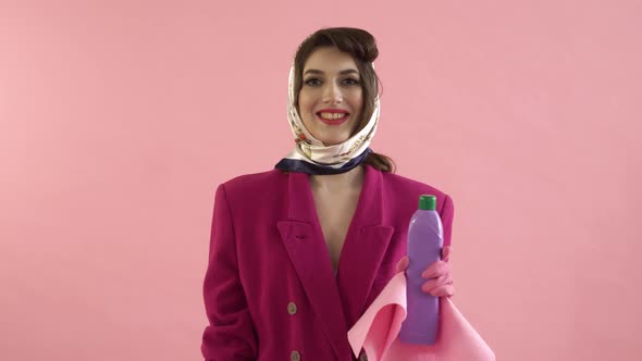 A Woman in Latex Gloves is Holding a Bottle of Household Chemicals and a Rag