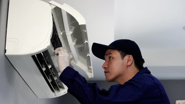 technician service checking and repairing air conditioner indoors