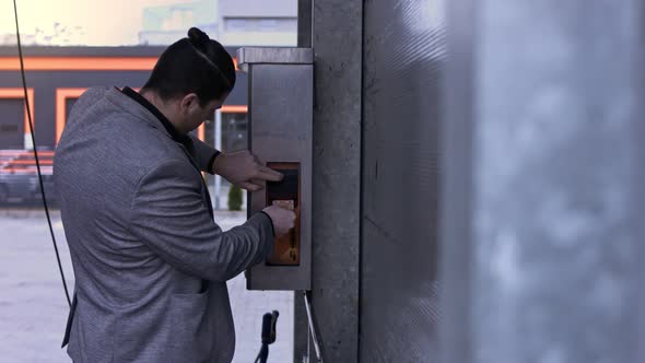 Man on Selfservice Carwash Inserts Cash for a Using on a Bill Acceptor alt