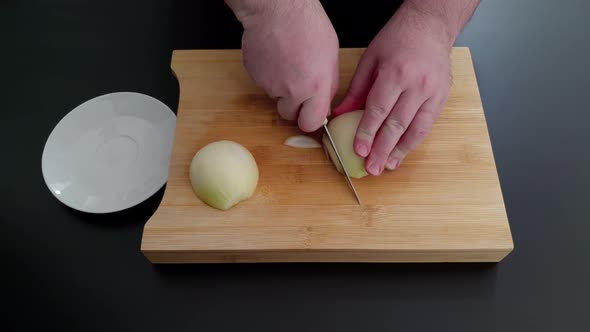 Close-up on hands cutting onion. High angle alt