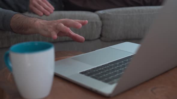 Lazy man lying on couch tries to reach the computer but can't make it alt