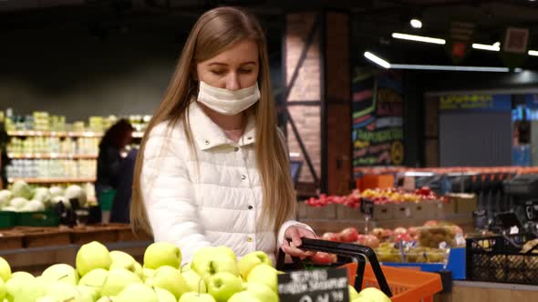 Young woman in a medical mask buys fruit. Self-isolation mode announcement  alt