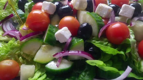 Olive oil pouring on a vegetarian salad with tomatoes,cucumber and onion. Slow motion 4k video