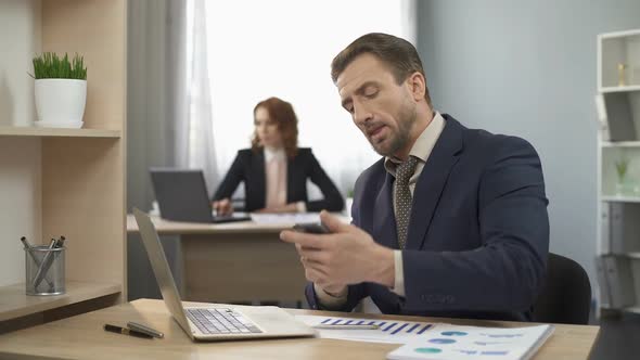 Male Employee Finishing Talk Over Mobile Phone, Working on Laptop, Satisfied alt