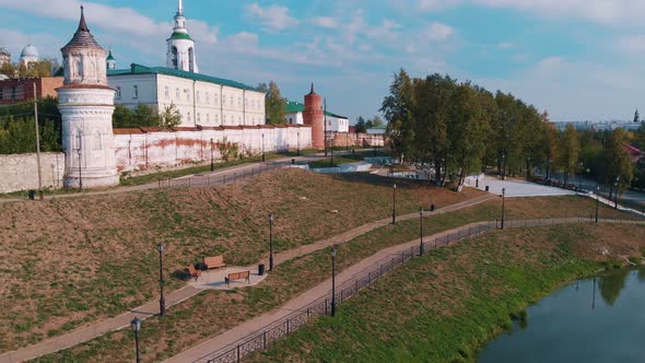 A Drone Flies Over a River to a White Brick Fortress with a Temple in Eastern Europe Near the Wall alt